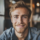 Homme souriant avec barbe claire, intérieur lumineux.